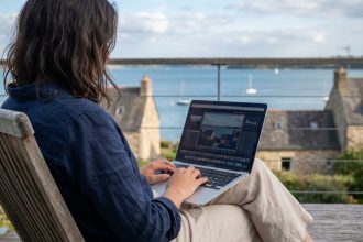 Femme assise avec ordinateur sur terrasse face à la mer à Vannes